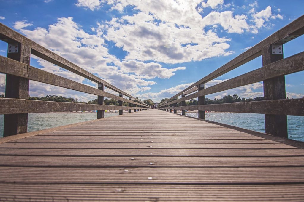 Explore endless skies from this serene wooden pier extending over calm waters.