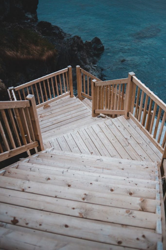 Peaceful wooden staircase descending towards a scenic, tranquil coastal view.